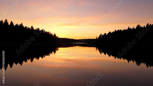 Silhouette of trees and sky mirroring in a calm lake