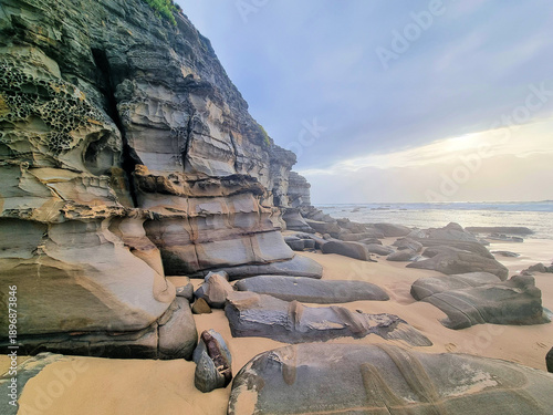 Eroded cliff face at Bar Beach Newcastle New South Wales Australia. Early morning with a grey cloudy sky.