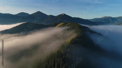 A scenic morning view of a misty mountain landscape featuring a serene lake and clouds over a valley in the summer nature of Scotland