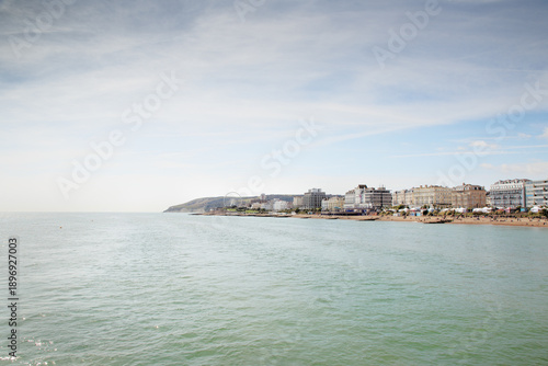 Sunny Coastal Town Beachfront With Ferris Wheel, Gentle Waves, And Oceanfront Buildings, Shoreline Panorama