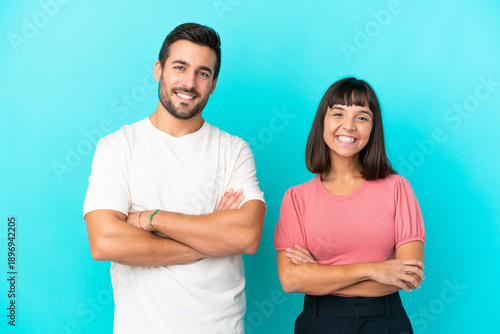 Foto Young couple isolated on blue background keeping the arms crossed in frontal pos