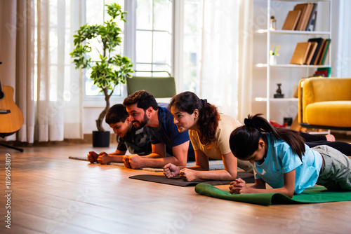 Indian young family performing plank exercise for core strength on floor at home