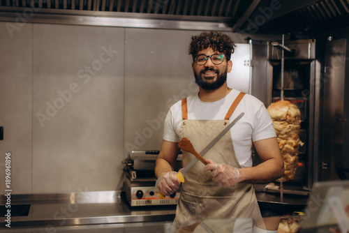 Fotografi Male chef holding knife and spatula in shawarma restaurant