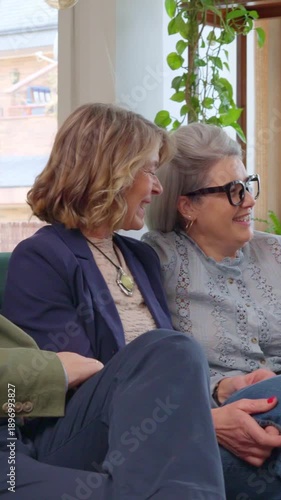 Two senior women talking and laughing on a sofa