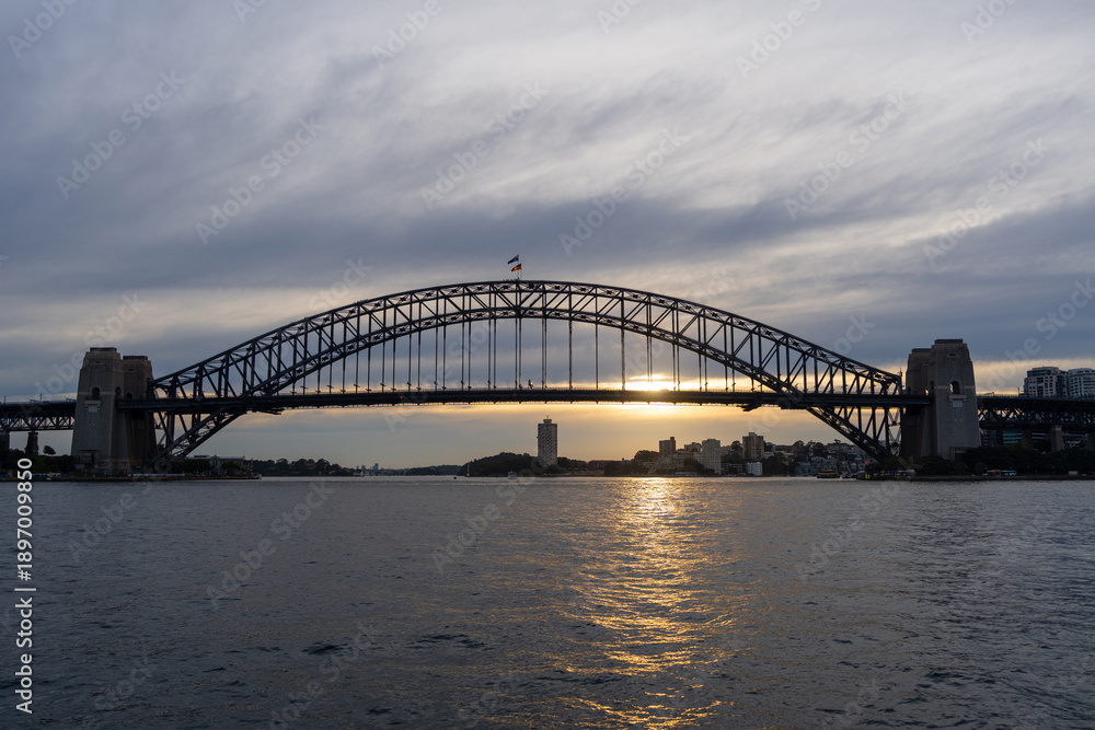 Fototapeta premium Sydney Harbour Bridge at sunset with golden reflections on the water
