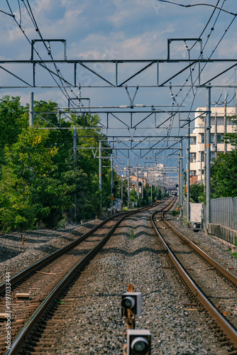 Railway tracks and overhead electric lines in Japan showing perspective and symmetry.Railway, Railroad, Tracks, Train lines, Kyoto, Japan, Transportation, Infrastructure, Electric wires, Overhead line