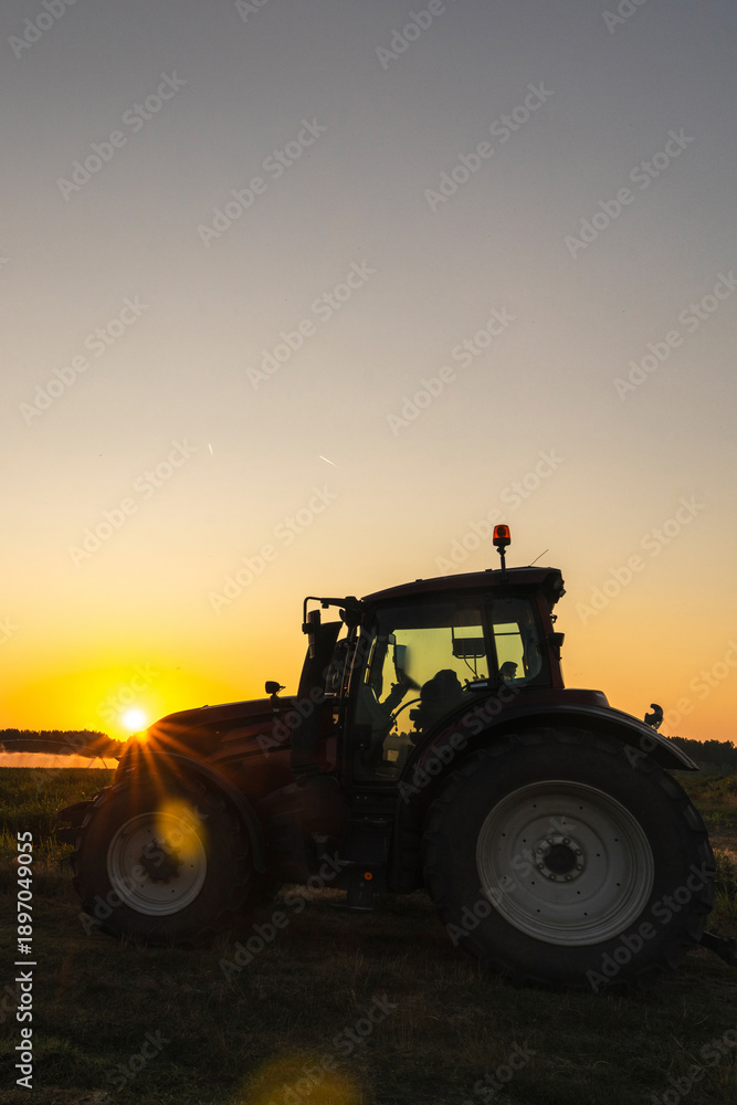 Obraz premium Tractor and agricultural watering pivot irrigation system on a corn field at sunset