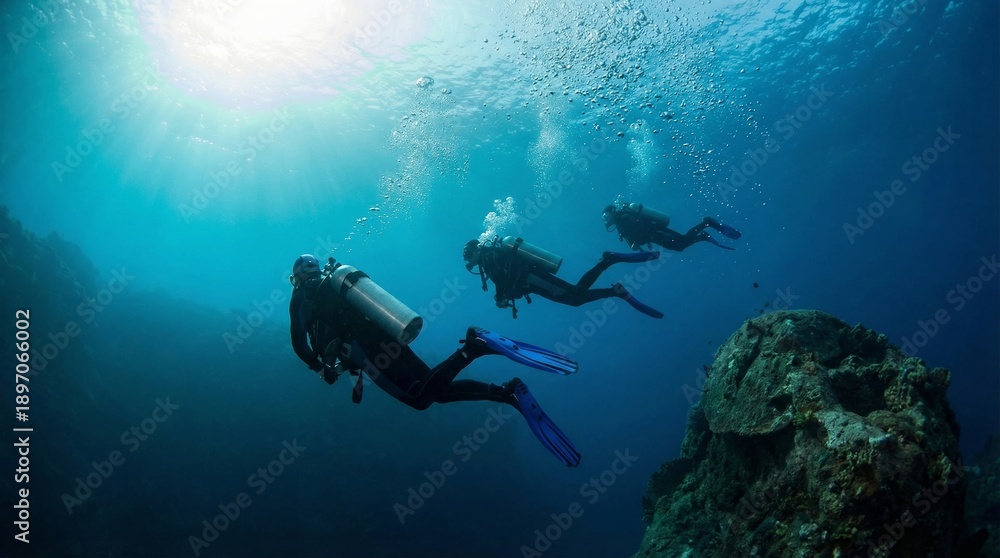 Obraz premium Three scuba divers exploring deep blue ocean with sunbeams and coral
