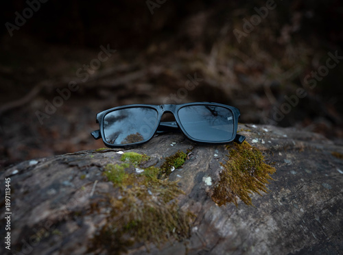 Sunglasses Resting on Mossy Rock in Forest Stream – Nature Escape Concept
