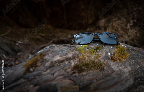 Sunglasses Resting on Mossy Rock in Forest Stream – Nature Escape Concept