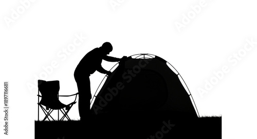 Silhouette of a person setting up a tent outdoors.