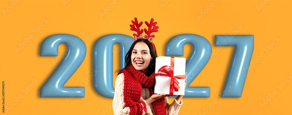 Naklejka premium A woman wearing festive attire holds a wrapped gift with a bow. She stands before large numbers representing the upcoming year. The background is bright and vibrant.