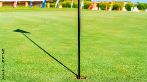 Golf action at the eighteenth hole with flag and green grass in clear weather