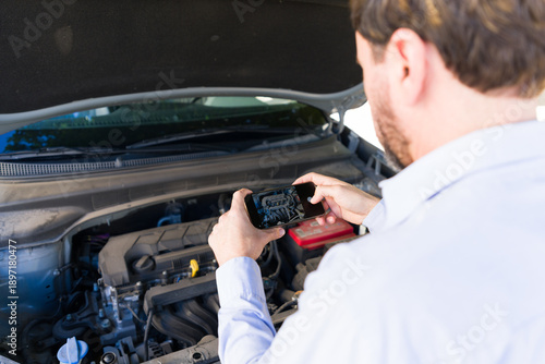 Принти на полотні Driver documenting car engine breakdown with smartphone, sending for a repair es