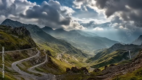 Mountain road winding through scenic valley under dramatic cloudy sky