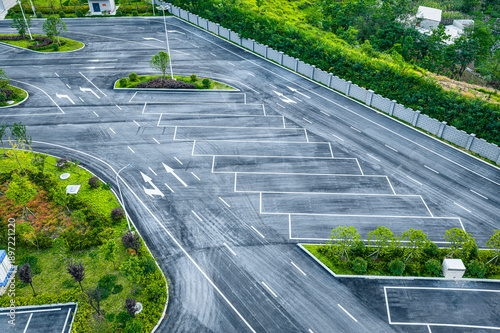 High angle view of an empty asphalt parking lot with white directional arrows and line markings in a modern facility.
