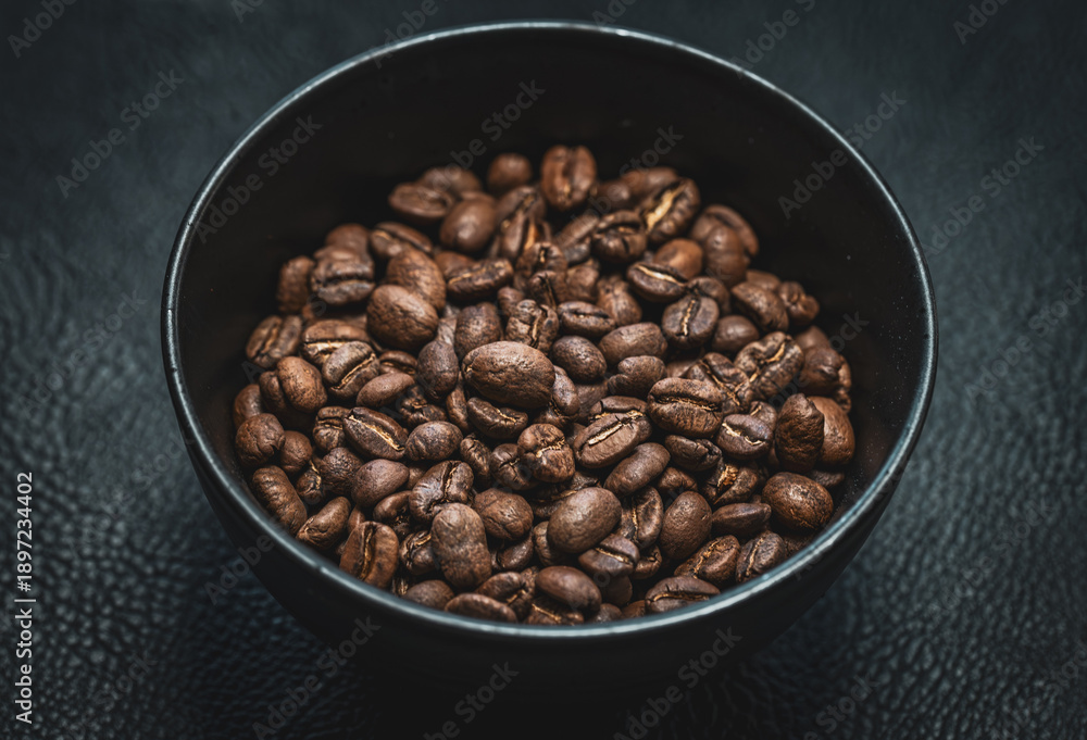 Fototapeta premium Bowl of roasted coffee beans on dark surface