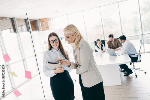 Canvas Print Two professional women discussing business ideas with digital tablet in an open