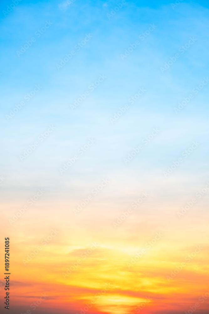 Obraz premium Sunset or sunrise sky with a vibrant gradient of orange, gold, and soft blue. Clear atmosphere with wispy clouds. Peaceful, natural light background. hope, freedom, new day Concepts, Vertical