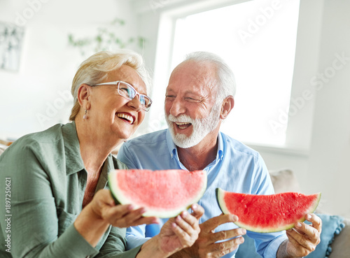 Wallpaper Mural Portrait of a happy senior couple embracing eating watermelon  and having fun at home Torontodigital.ca