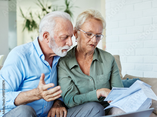 Wallpaper Mural Senior couple checking bills and calculating expenses using a laptop at home, debt taxes concept, worried married elderly couple Torontodigital.ca