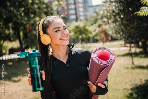 Young woman outdoors with fitness gear smiling during outdoor workout in sunny park city morning exercise motivation wellness