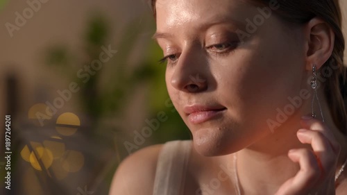 Portrait of a gorgeous young woman with natural makeup and braided hair turning her head while looking away in warm, golden hour sunlight