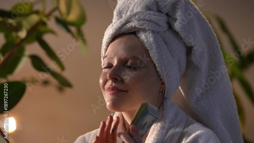 Beautiful woman in a bathrobe with a towel on her head counting a stack of dollar bills. Successful young adult enjoying her earnings