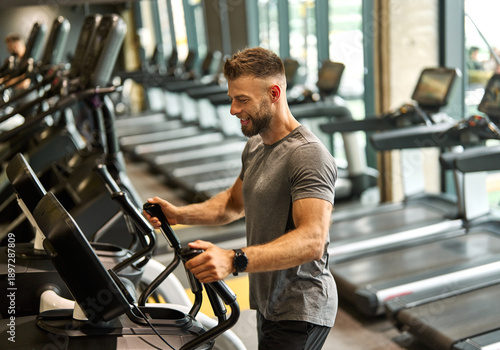 Fotografía Portrait of a young man exercising on an elliptical trainer in a gym, running us