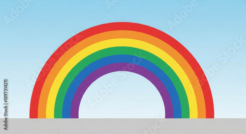 Vibrant rainbow arc against a serene light blue sky background with a grey surface