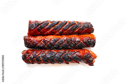 Three charcoal burned sausages stacked and isolated on white background, soft focus close up