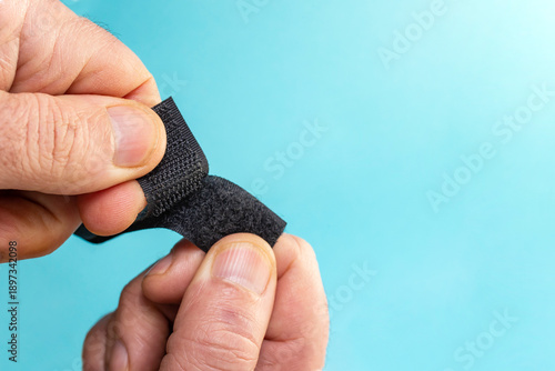Foto Velcro fastener tape with hook and loop tape openeb by male fingers on blue back