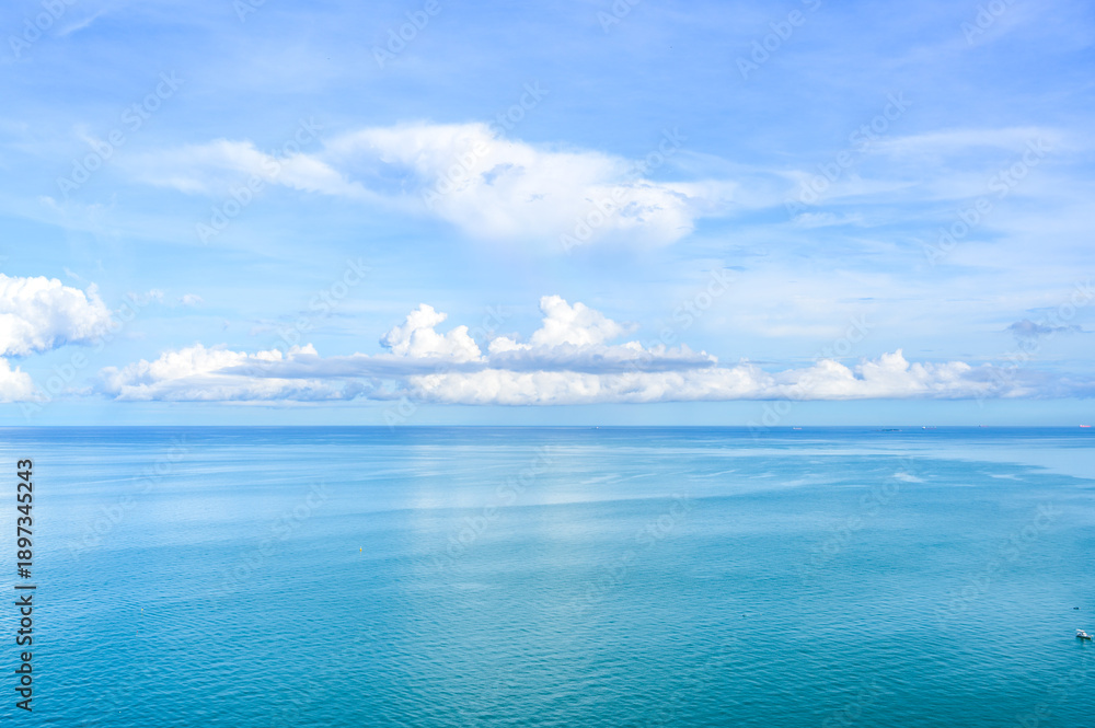 Obraz premium White clouds in sky over seascape on sunny day in Pattaya, Thailand. beautiful landscape of tropical sea water with reflection of sunlight. copy space.