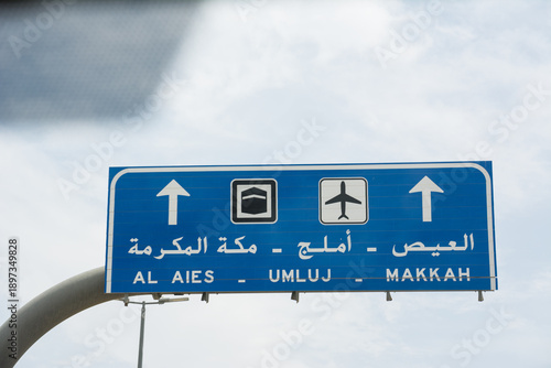 Road sign with directions in English and Arabic along highways in Saudi Arabia with desert landscape around