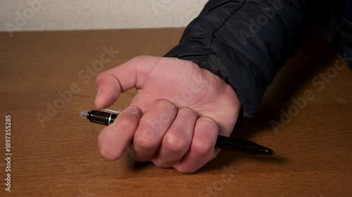 Person nervously clicking retractable pen on desk