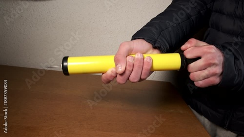 Person's hands pumping air with a yellow ball pump