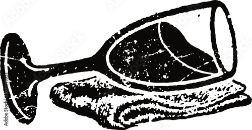 Wine glass lying on side with liquid spilling onto folded cloth, monochrome vintage