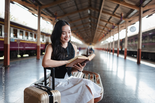 Young woman reading book while waiting for train
