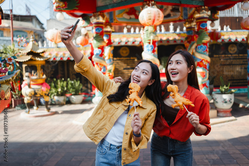 Happy young Asian women taking selfie with street food