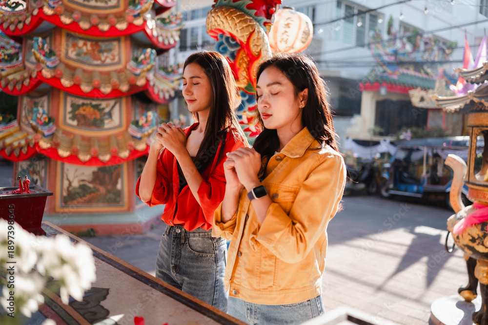 Obraz premium Young women praying at a Chinese temple in Thailand