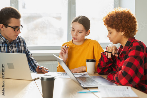 Teamwork brainstorm. Diverse colleagues working together discuss financial statistics. Group of happy young modern people sitting in creative office discussing business. Young professional team