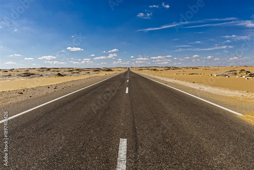 The road - super-quality highway - in the desert with blue cloudy sky in the background, between Dirrot City and Farafra oasis in Egypt
