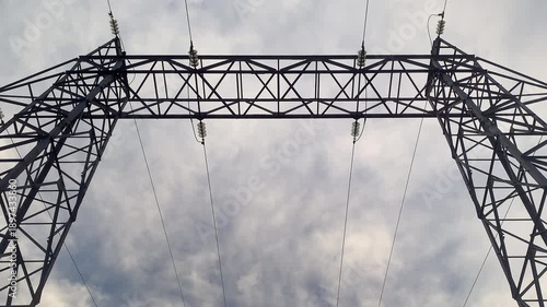 Smooth zoom out timelapse of electricity tower silhouetted against dramatic sky