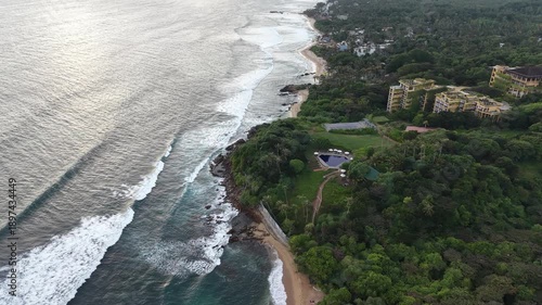 Aerial View of Surfers and Luxury Villa with Pool on Tropical Beach at Sunset, Sri Lanka