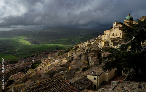 Gangi (Sicily) on a cloudy day with a green hill in the background. The hill is covered with trees and houses