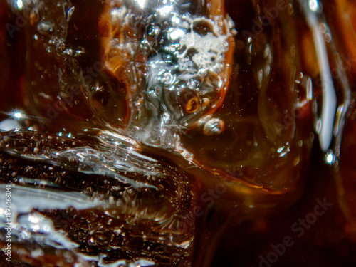 Ice cubes melting in black coffee macro background