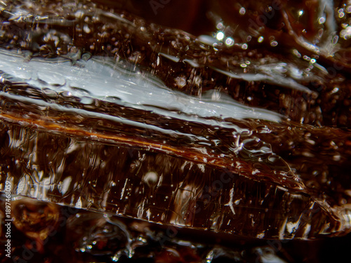 Ice cubes melting in black coffee macro background
