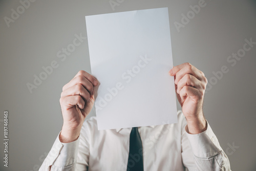 Businessman hiding face behind blank white paper sheet mockup