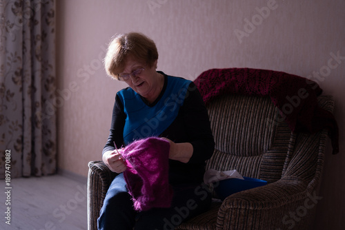 Elderly woman knitting in a chair