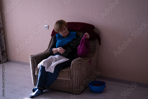 Elderly woman knitting in a chair